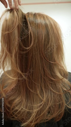Hairdresser moves finished colored hair by hand to show the final result in a beauty salon. Vertical reveal scene for beauty, fashion, styling, advertising and salon marketing