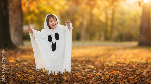 Child celebrating halloween dressed as ghost in autumn park