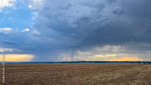 Dramatic Sky Over Fields with Rain and Sunbeams