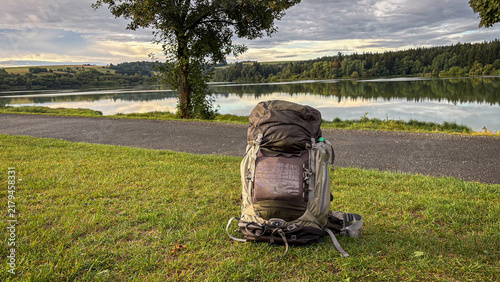 Backpack resting on grass by serene lakeside view