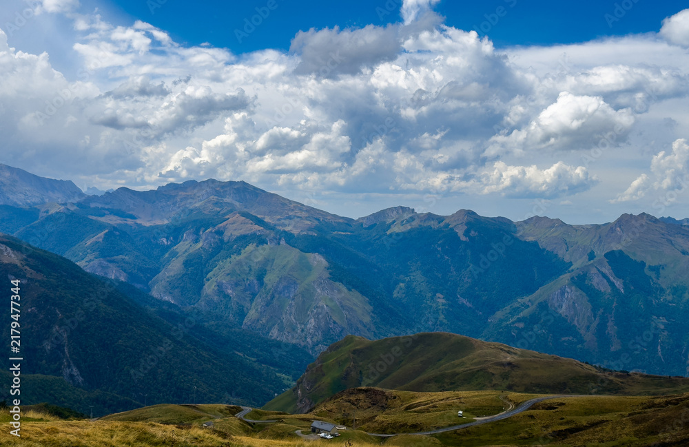 Fototapeta premium serene mountain range overlooking the valley with a road and clouds in a natural outdoor setting, high vantage point, travel adventure nature theme, green and blue tones.