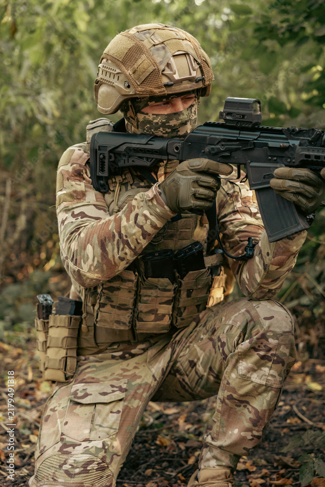 Obraz premium Armed military operator aiming a rifle during a combat patrol mission.