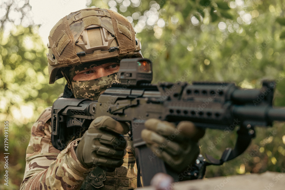 Obraz premium Armed military operator aiming a rifle during a combat patrol mission.