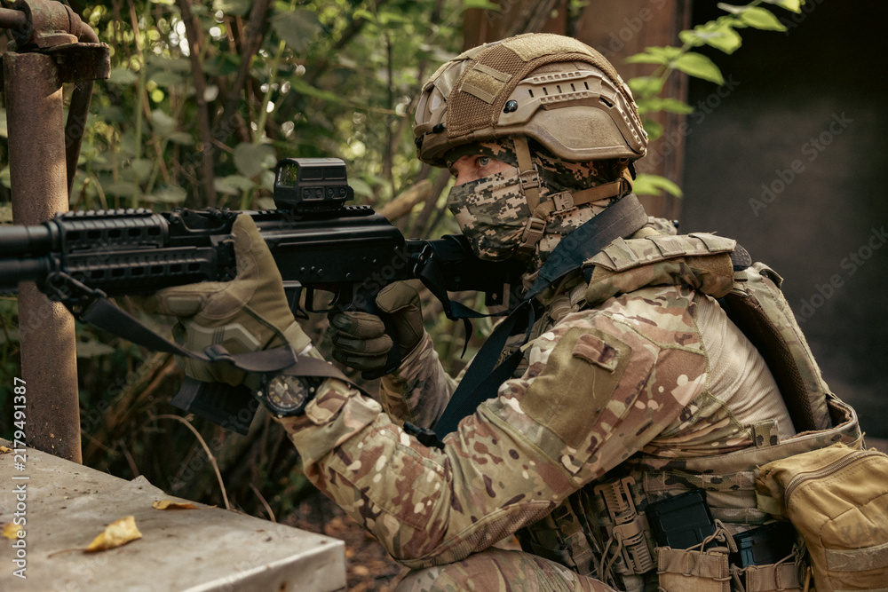 Obraz premium Armed military operator aiming a rifle during a combat patrol mission.