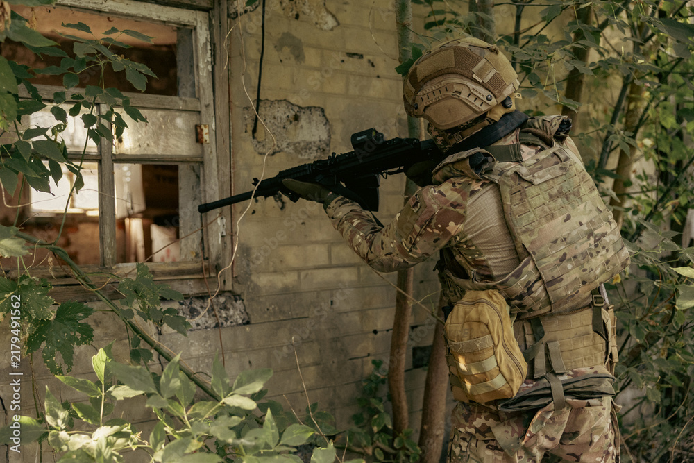 Obraz premium Armed military operator aiming a rifle during a combat patrol mission.