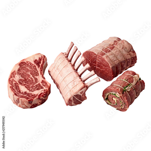 Assortment of raw meat cuts including ribeye steak, lamb rack, and beef roast on white