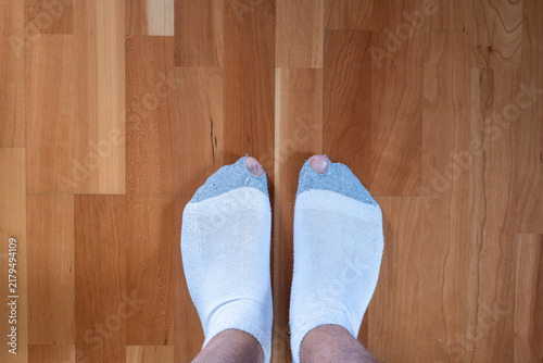 Bild auf Leinwand Top view of feet wearing worn socks with holes at the toes standing on a natural