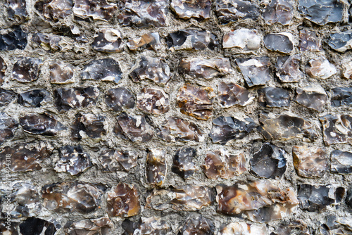 Obraz na plátně Full frame background texture of a historic knapped flint stone wall with rough mortar joint construction detail