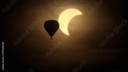 Quadro su tela Hot air balloon silhouette flying past a solar eclipse crescent sun