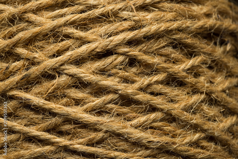 Obraz premium Macro closeup of natural brown jute twine rope texture,A detailed close-up photograph showcasing the coarse, fibrous texture and twisted pattern of natural brown jute rope wound tightly together.