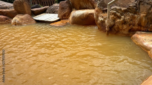 Canvastavla Muddy orange mineral water in a rustic open-air hot spring bath surrounded by na