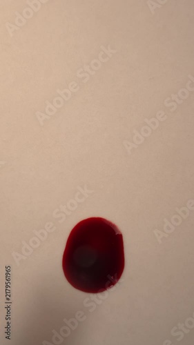 Dark blood dripping onto blank empty off-white surface for forensic discovery, top view zoom in slow motion, top copy space, vertical video
