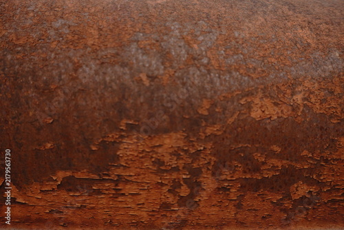 A close-up full frame abstract shot of peeling orange paint on a rusty metal surface