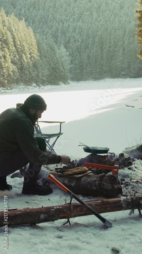 Man cooking food over campfire in winter