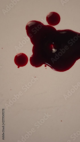 Blood dripping and impacting pool on light surface for crime scene evidence, top view slow motion, bottom copy space, vertical video