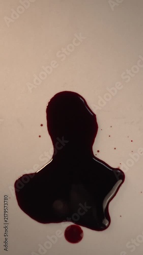 Blood dripping and accumulating into pool on off-white surface for forensic investigation, top view zoom in slow motion, top copy space, vertical video