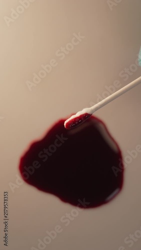 Close up of cotton swab collecting blood for crime scene investigation and lab testing, top view, blue gloved hand, vertical video