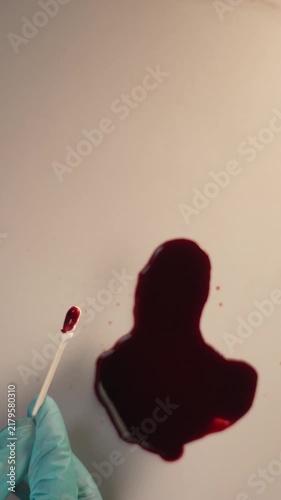 Cotton swab collecting blood sample for crime scene evidence and laboratory analysis, top view, blue gloved hand, wide top copy space, vertical video