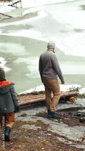 Father and son walking towards a frozen lake in winter