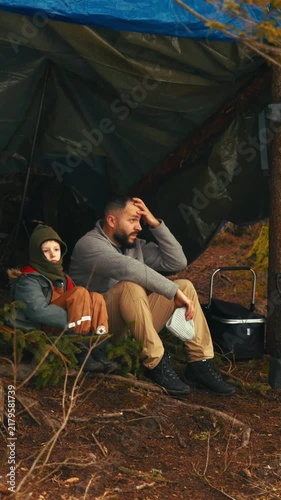 Father and son camping in a forest shelter