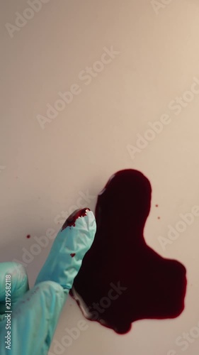 Gloved finger collecting blood specimen for crime scene evidence and lab analysis, top view slow zoom in, top copy space, vertical video