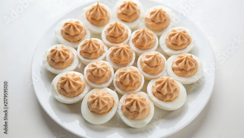 Freshly prepared deviled eggs arranged neatly on a white serving plate with boiled eggs