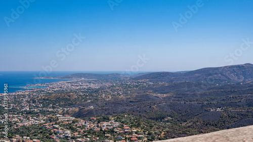 Obraz na płótnie Blackened hills and burned vegetation above coastal settlements and blue sea, Ch