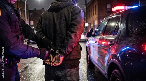 Close up of suspect getting arrested and handcuffed by police officer on urban street
