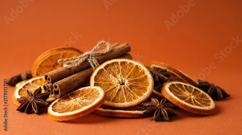 Dried orange slices and cinnamon sticks arranged on an orange background  