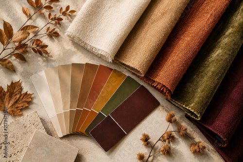 Warm autumn color palette with textured fabric swatches, color sample cards, natural stone materials and dried leaves. Earthy seasonal tones for fashion, textile and interior design inspiration.