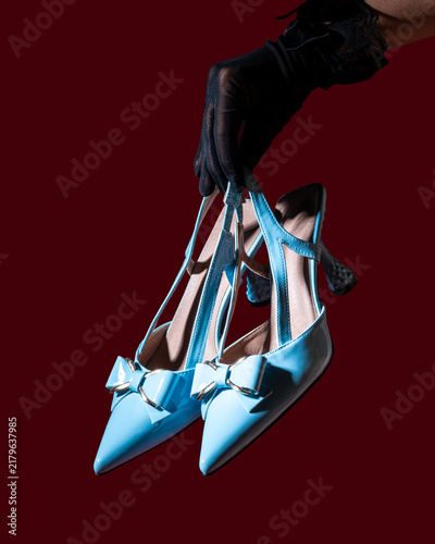 Hand in glove holding two blue shoes