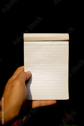 Close up of hand holding notepad isolated on black background