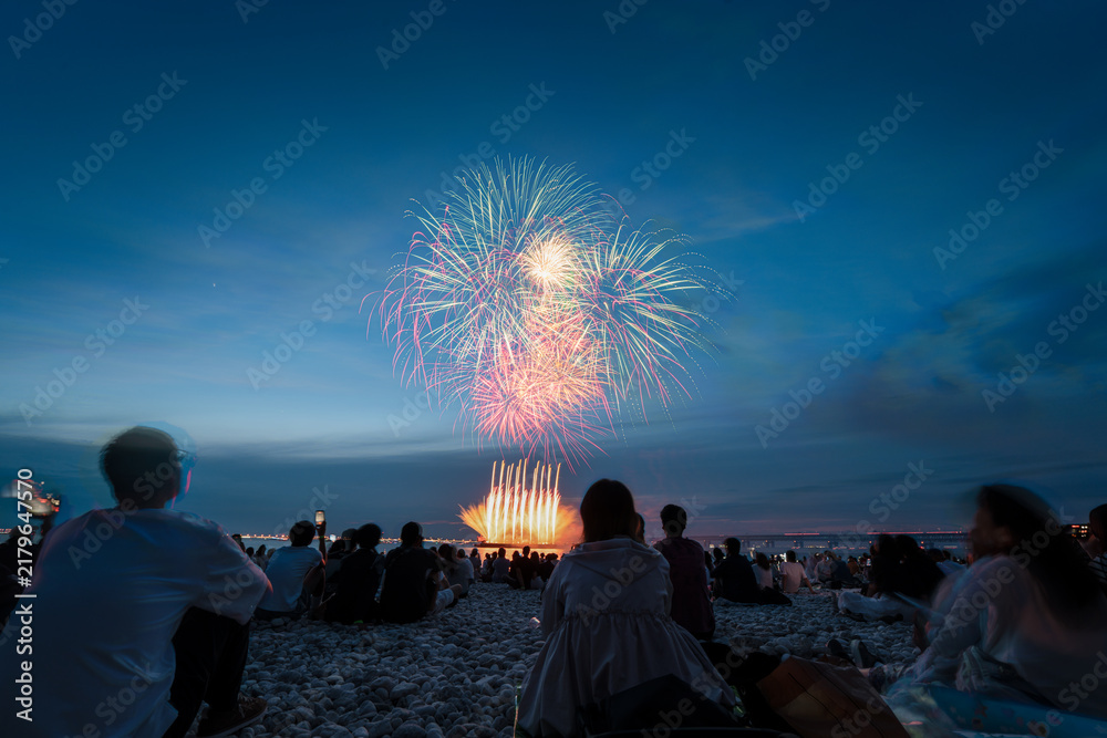 Obraz premium Multicolor fireworks and launch fans over Osaka beach crowd