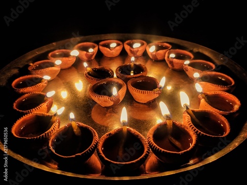 Foto A close-up shot of multiple traditional earthen oil lamps, known as Diya, beautifully illuminated and arranged on a metallic tray in the dark