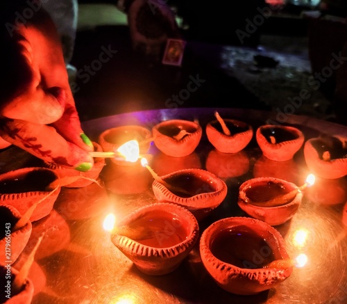 Quadro su tela A close-up shot of multiple traditional earthen oil lamps, known as Diya, beautifully illuminated and arranged on a metallic tray in the dark