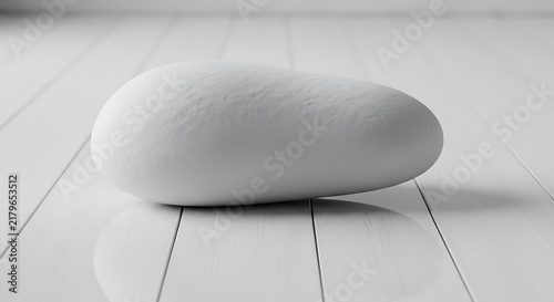 Minimalist smooth white stone resting on a clean white wooden floor surface providing a peaceful and serene conceptual zen background image