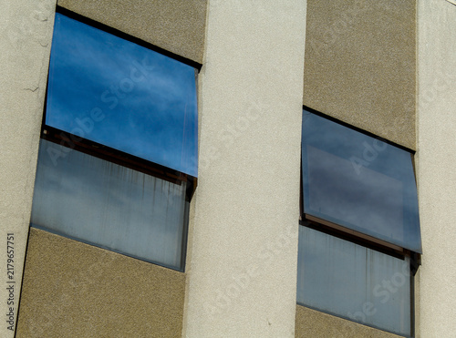 Modern Concrete Building Facade with Open Glass Windows Reflecting Sky