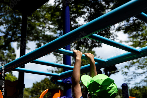 Fotografie Child playing on monkey bars in a playground on a sunny day