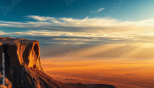 Dramatic desert cliff landscape at sunset with golden light and vast horizon view