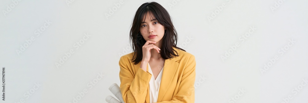Obraz premium Thoughtful young woman in yellow blazer portrait on neutral background for professional portrait and fashion design and editorial use
