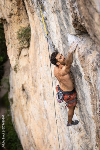 Фотография Shirtless climber grips a rocky cliff