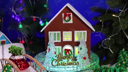 In the center of the Christmas village, among the decorated Christmas trees, Santa Claus comes running to a brown house