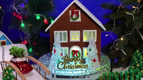 In the center of the Christmas town, among the decorated Christmas trees, Santa Claus comes running to a brown house