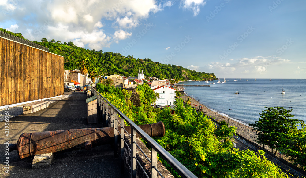 Fototapeta premium Scenic view of the coastline and town of Saint-Pierre in Martinique, featuring an old cannon at the historic fort ruins and the Caribbean sea.