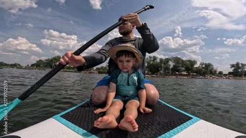 Father and son paddleboarding on lake