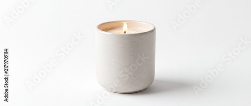 White ceramic candle holder with lit candle on white background