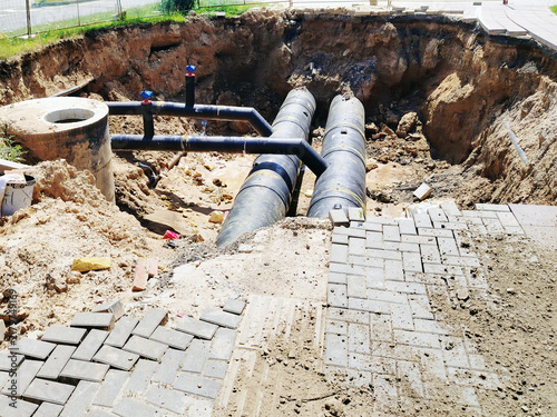 Underground Pipes and Excavation at Urban Construction Site With Exposed Sewer Lines and Paving.