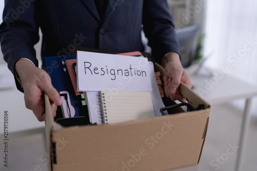 Asian businessman carrying resignation box with personal belongings leaving office after quitting job with copy space