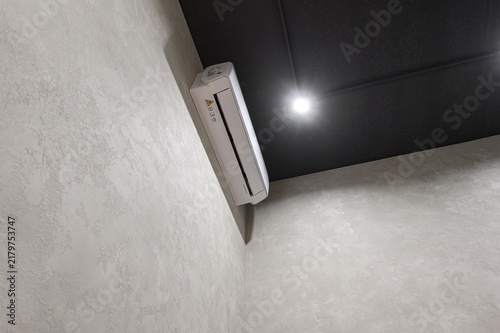 Foto sleek white wall‑mounted air conditioner sits in corner against textured off‑white wall