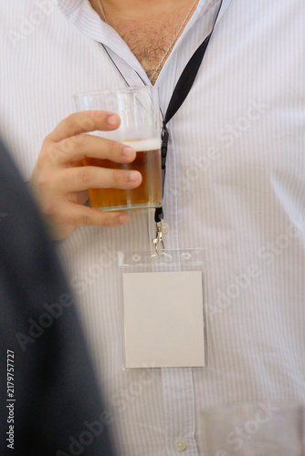 Man holding beer and wearing blank badge at event